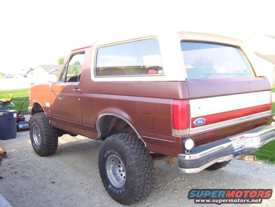 1990 Ford Bronco, brown and white, lifted with large tires, rear 3/4 view
