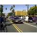 2007 Ford Ranchero - A street scene with multiple classic cars and onlookers on a sunny day.