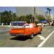 2007 Ford Ranchero - A bright orange coupe utility with flame decals is seen from the rear on a city street.
