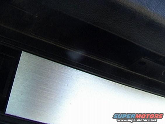 Close-up of a car's interior trim panel showing a brushed metal insert and black textured material