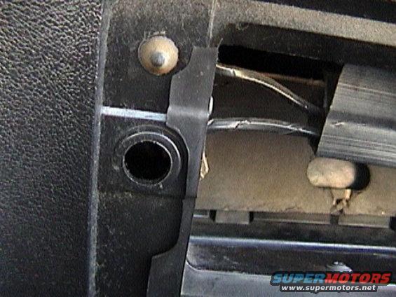 Close-up of a car's interior panel with a clip and some wires visible