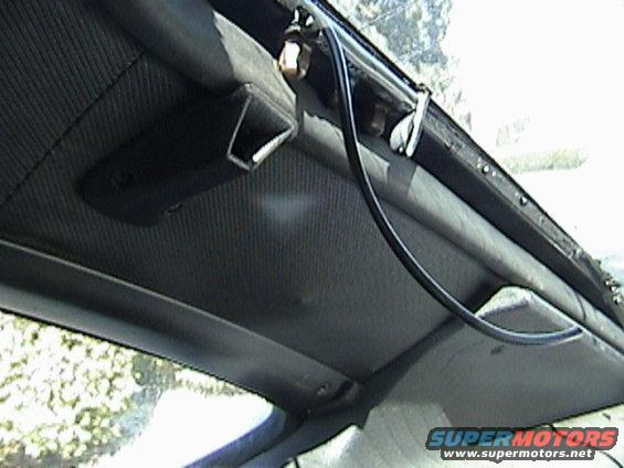Car interior ceiling with textured fabric, black plastic trim, and a black wire running along the edge