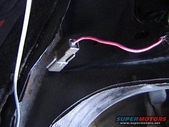 Wiring harness clip with pink wire attached to vehicle frame