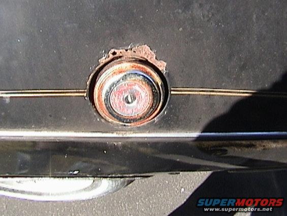 close-up of a rusty fuel filler cap on a dark car body