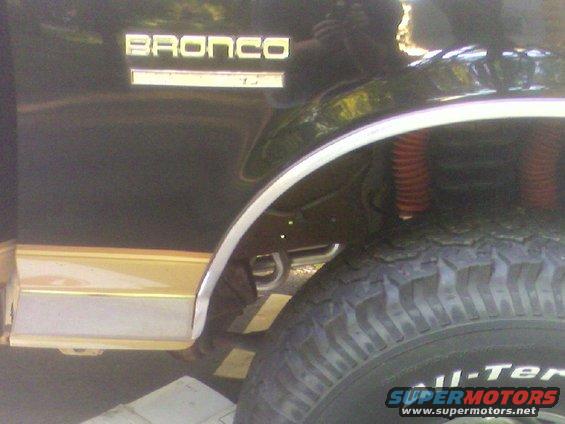 1990 Ford Bronco side view showing rear fender, gold trim, and tire with "All-Ter" text