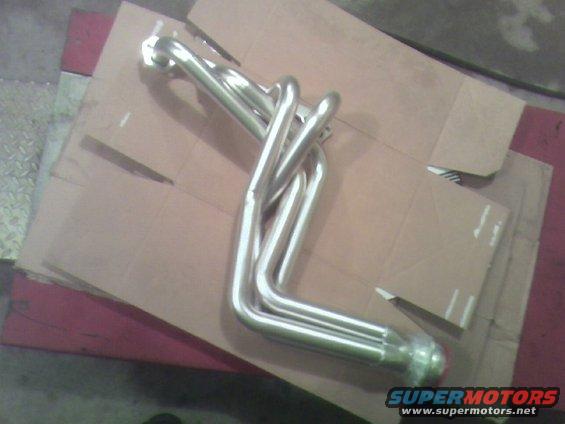 Shiny metal exhaust headers on cardboard