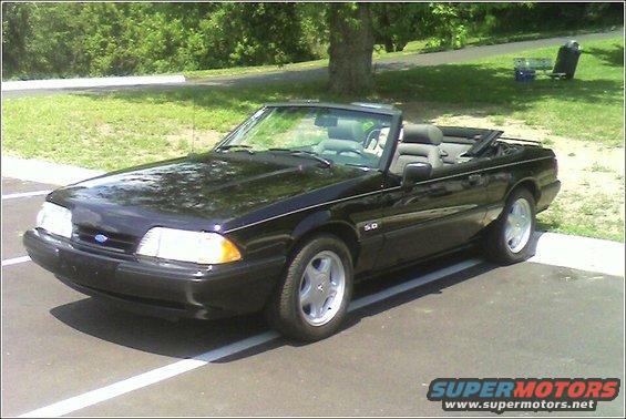 Black convertible with a gray interior parked on asphalt. The "5.0" badge is visible on the fender