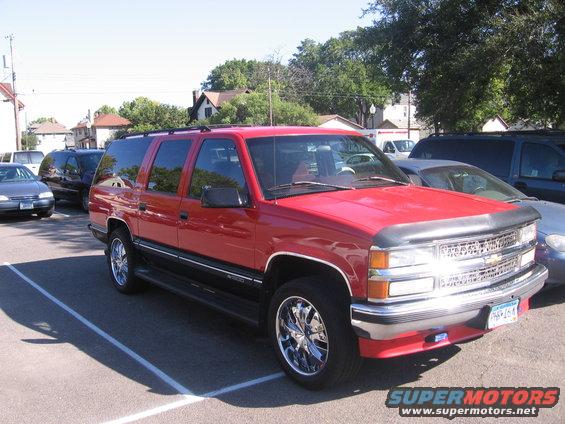 Red SUV with chrome wheels, front 3/4 view. License plate PHR-164