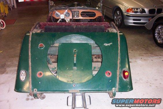 1964 Morgan 4/4 rear view showing spare tire well and taillights; other cars visible in background