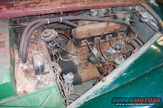Green car engine compartment with rusty engine and wiring