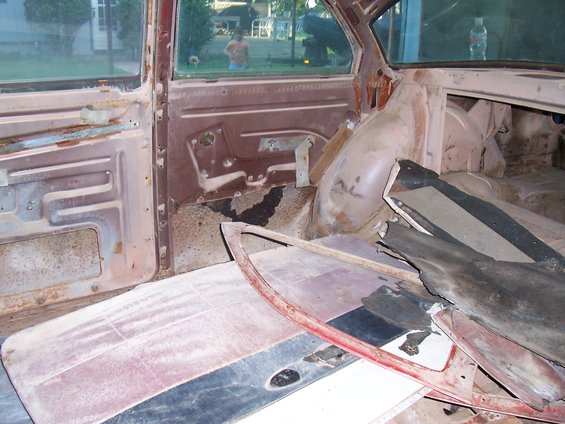 Interior of a car with rust and debris. Door panel and floor are visible