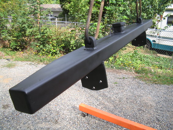 black metal bumper hanging from chains, with mounting brackets visible. An orange engine hoist is below