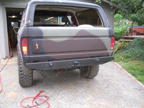 Rear view of a 1978 Ford Bronco with camouflage paint and a custom bumper