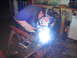 1979 Ford Bronco - Metal beam being welded in a workshop setting with welding equipment visible.