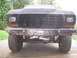 1979 Ford Bronco - The front grille and custom bumper of a 1979 Ford Bronco are visible, along with its large off-road tires.