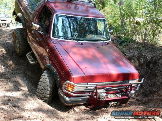 Red Ford Bronco stuck in dirt with another vehicle in the background