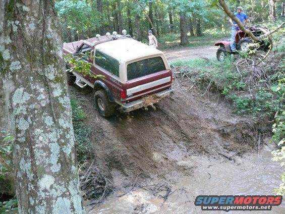 Ford Bronco going down a muddy hill with an ATV behind it