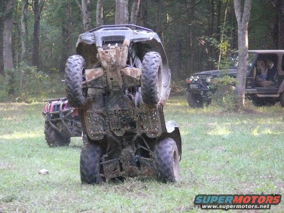 Four-wheeler on its side, with another ATV and two Jeeps in the background