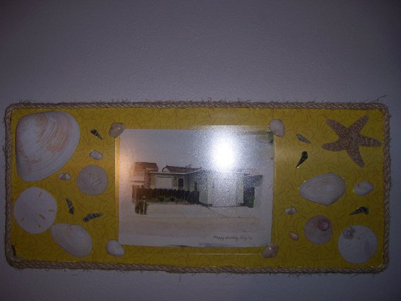 Photo of a beach house with a fence in front, decorated with shells and a starfish
