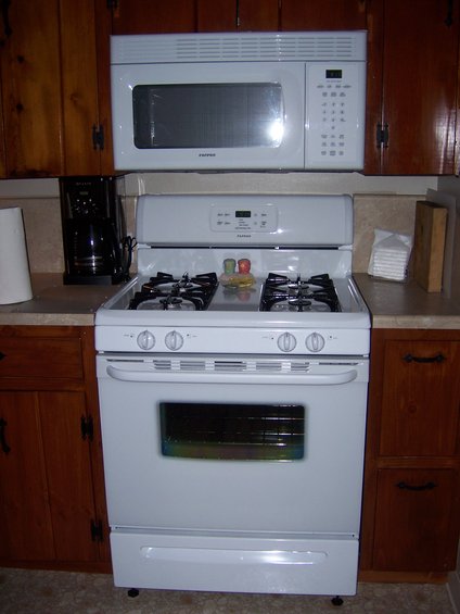 White gas range with microwave above, set in wooden cabinets