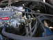 1978 Ford F-250 - Close-up view of an Edelbrock carburetor and associated engine components, including throttle linkage and springs.