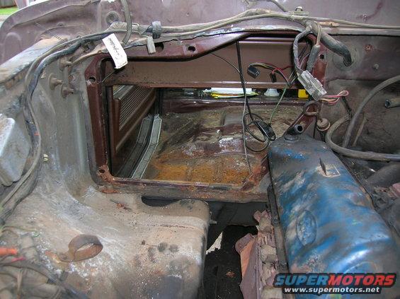 View of a vehicle's engine bay and firewall area, showing exposed wiring and parts of the engine