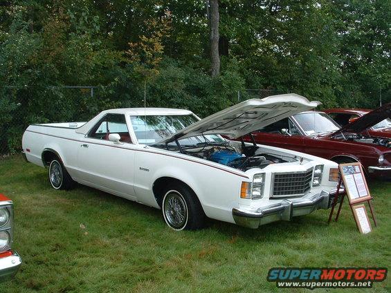 White 1977 Ford Ranchero with hood open, red pinstripes, wire wheels, parked on grass