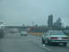 2000 Ford Crown Victoria - A white coupe drives on a wet highway, with traffic and construction cones visible.