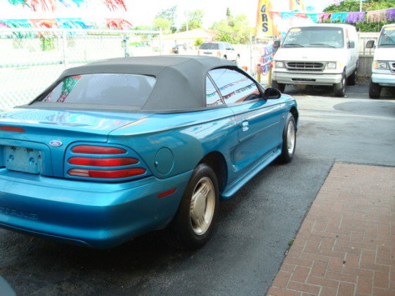 Blue convertible with black top, rear quarter view. "Mustang" text visible on rear bumper