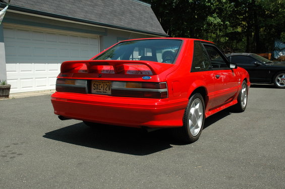 Red 1993 Ford Mustang rear view, showing a spoiler and license plate SXC-12V