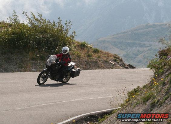 Motorcycle with rider wearing a white helmet and red jacket on a winding mountain road