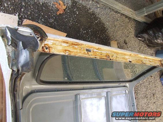 rusted door frame with window opening, showing metal and wood structure
