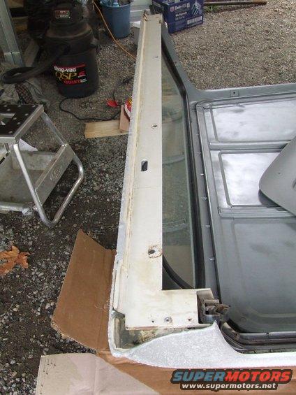 Car door frame with white trim and exposed metal, viewed from the side