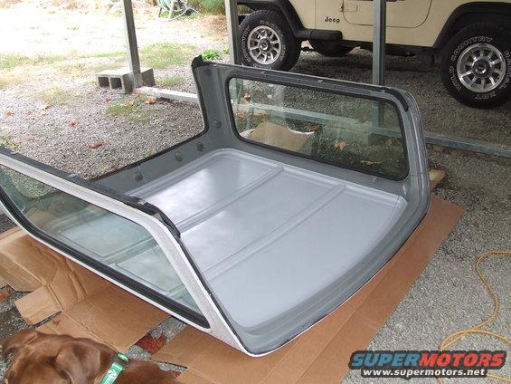 Jeep Wrangler removable hardtop sitting on cardboard, with a Jeep visible in the background