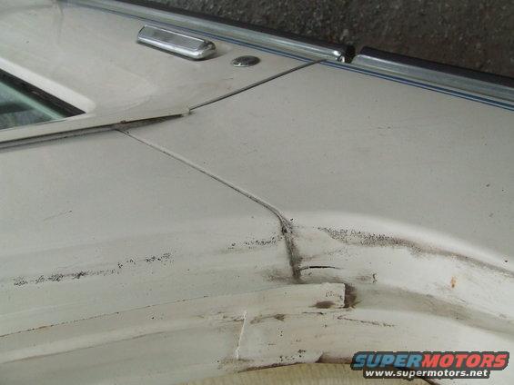 White vehicle door seam with chrome trim and visible damage