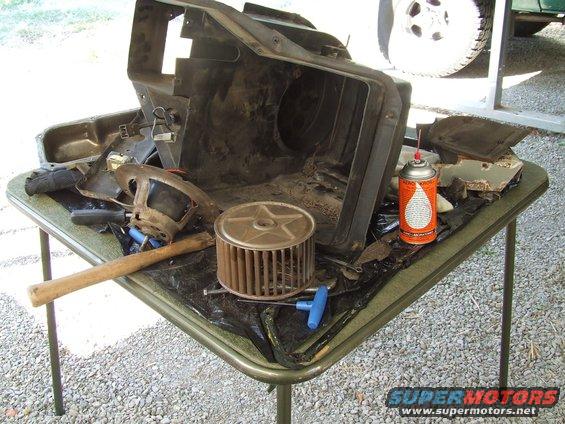 Disassembled HVAC unit and parts on a table, with a can of spray lubricant