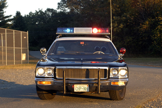 1973 Dodge 1500 police car front view with light bar and push bumper. License plate reads CHP-NH