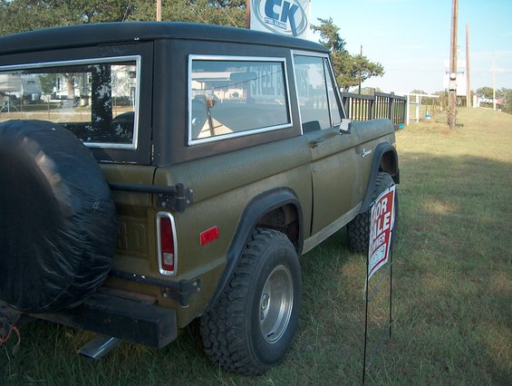 1979 Ford Bronco with spare tire on rear, parked on grass with a 'For Sale' sign