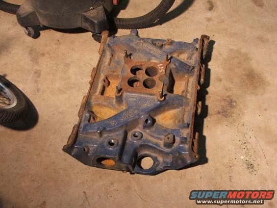 Blue engine intake manifold with four carburetor bolt holes