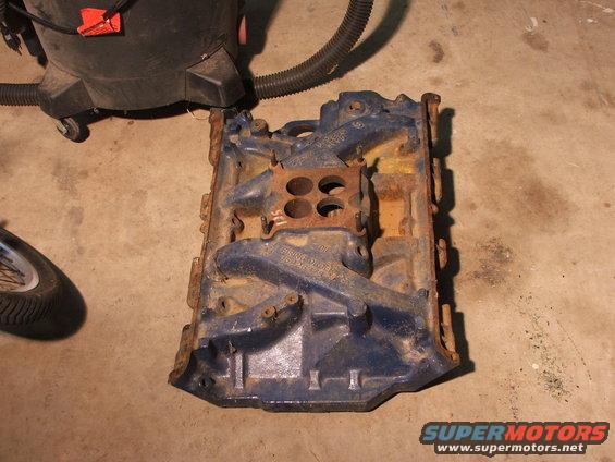 Blue painted engine intake manifold with four bolt holes on top