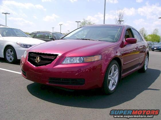 Red sedan parked in a lot, front 3/4 view. Other cars visible