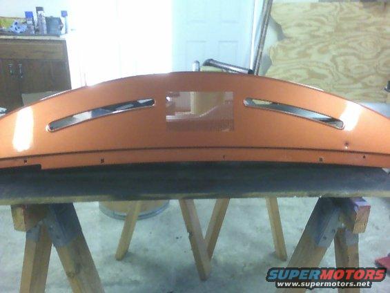 Orange dashboard section with two horizontal slots and a central rectangular cutout, resting on sawhorses