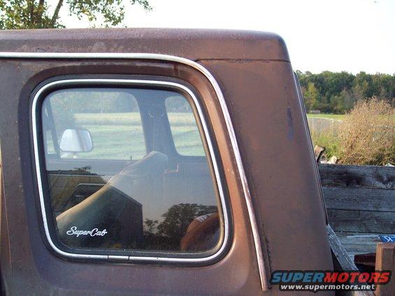 1978 Ford F-250 SuperCab rear window trim and reflection. Brown paint shows rust