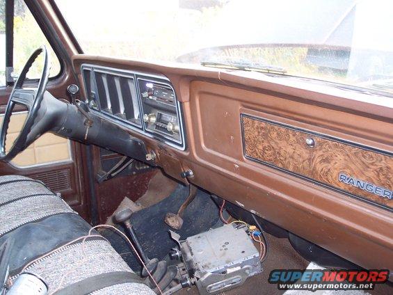 Interior of a truck with woodgrain trim and a "RANGER" badge on the dash. Aftermarket radio is visible