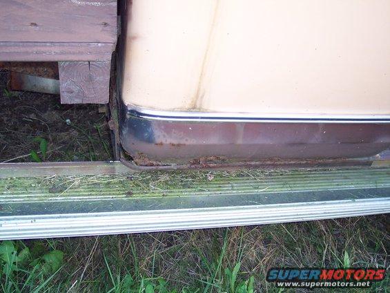 Truck lower body panel with rust and chrome trim, viewed from the side