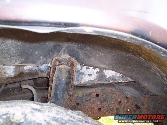 Rusty frame and wheel well interior of a vehicle, showing significant corrosion