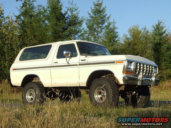 White 1979 Ford Bronco with lifted suspension parked in grassy field