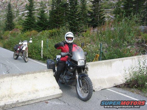 Black motorcycle with rider stopped at concrete barrier on a road