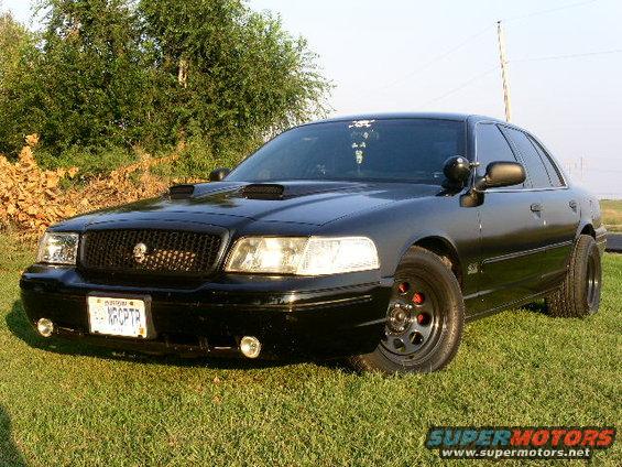 2001 Ford Crown Victoria with custom grille, hood scoops, and aftermarket wheels parked on grass