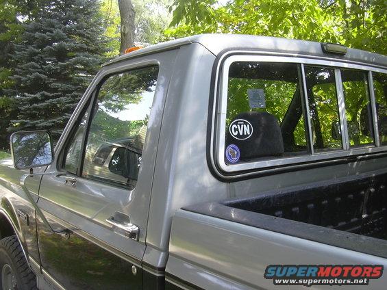 Silver and black pickup truck side view, showing door handle, side mirror, and rear window with stickers